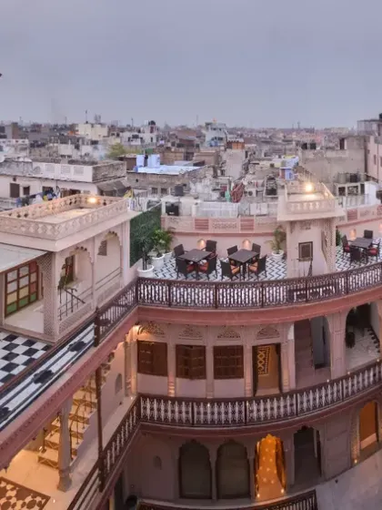 A panoramic view from the terrace, showing the dining areas set against the backdrop of Old Delhi's skyline. Guests can watch the traditional pigeon flying races or fly kites from this rooftop space.