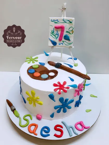 A painting-themed cake for a 7th birthday. The design features a fondant easel and palette, with colorful paint splatters adding a fun and creative touch to the whipped cream frosting.