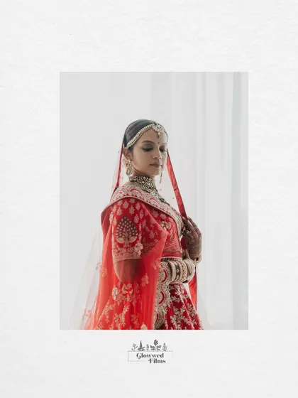 A minimalist portrait of the bride, Krutika, against a clean white background, letting her red lehenga and beauty take center stage.