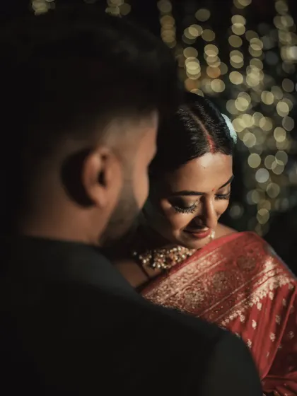 An intimate, over-the-shoulder shot that focuses on the bride's serene expression as she leans into her partner. The bokeh lights add a touch of magic to the evening.