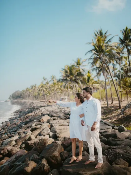 A couple looks out towards the future, standing on a rocky outcrop overlooking the ocean.