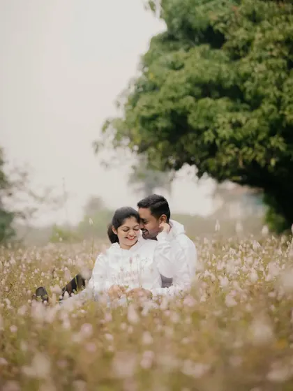 A couple shares a tender moment, sitting together in a beautiful field of white wildflowers. This style is perfect for soft, natural, and romantic pre-wedding portraits.