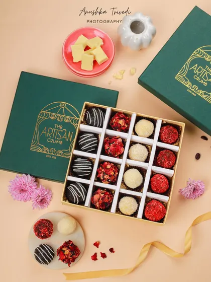 A top-down flat lay of the artisan chocolate box, showing the beautiful packaging and the colorful truffles inside.