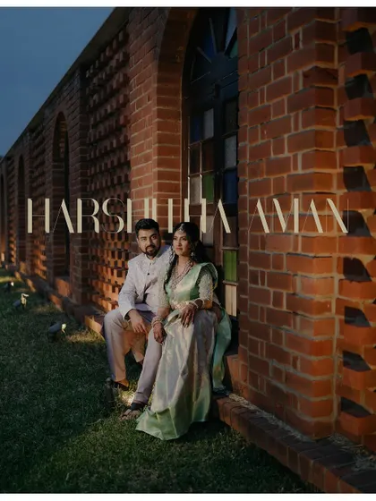 A dramatic evening portrait of the couple from their engagement shoot. The architectural details of the brick wall and the warm lighting create a sophisticated and romantic atmosphere.