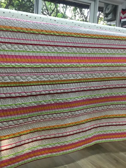Another view of the colorful striped quilt on the frame.