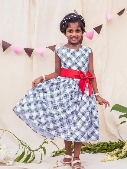 A classic black and white checkered A-line dress, brightened up with a bold red satin sash. This versatile dress is perfect for school picture day or a family gathering.