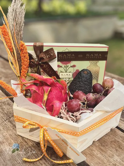 A wellness-focused get well soon hamper, featuring fresh fruits like dragon fruit and grapes alongside luxurious Kama Ayurveda products.