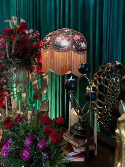 A collection of vintage props, including a floral lampshade, old books, and candle stands, are used to create a charming and nostalgic vignette.