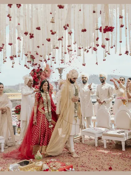 Nikita and Rishabh taking their first steps as a married couple during their pheras. The shower of petals adds a sense of blessing and celebration.