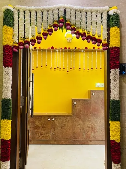A beautiful floral garland framing the doorway for a housewarming ceremony, creating a warm and welcoming entrance.