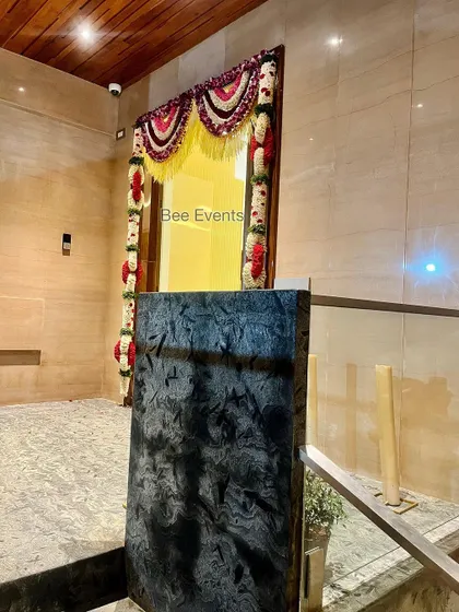 A wide shot of a doorway adorned with traditional flower hangings. The decor adds a festive touch while allowing a glimpse into the beautifully lit home interior.