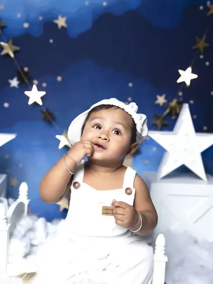 Looking up at the stars in this dreamy night-sky themed sitter session. The soft clouds and hanging stars create a serene and magical atmosphere.