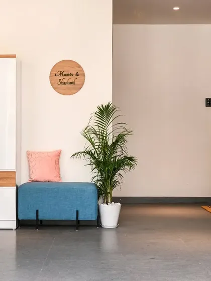A wide view of the foyer, showing the functional shoe storage and seating area. The potted plants add a touch of green and make the entrance feel fresh and welcoming.