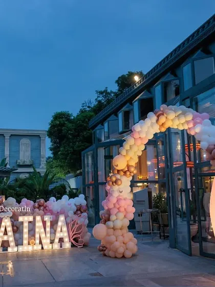 A wide-angle view of the outdoor setup, showing the marquee letters, the balloon arch, and the large butterfly wing prop creating a cohesive and impressive entrance.