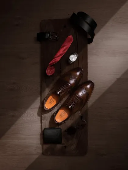 A top-down flat lay of men's formal accessories, with the leather shoes as the centerpiece. This type of shot is great for storytelling, suggesting a complete, sophisticated look for the modern gentleman.