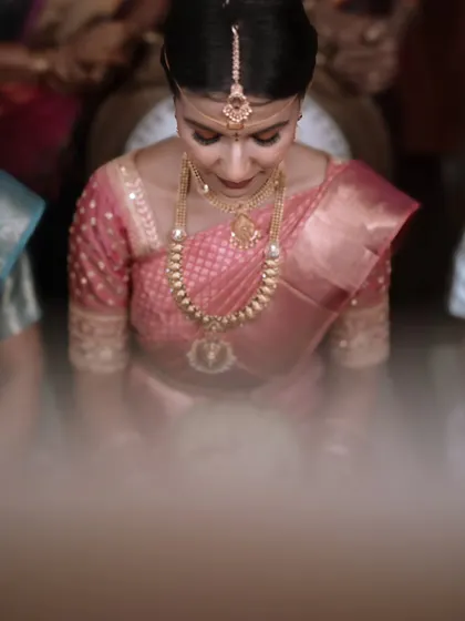 A high-angle shot of the bride during a ceremony. The soft focus on the foreground draws the viewer's eye to her serene expression and beautiful attire.