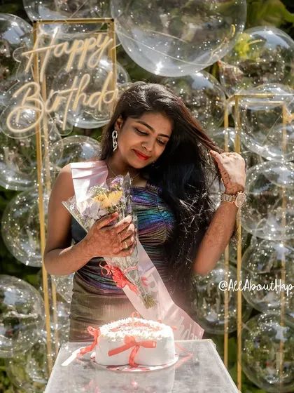 A happy client posing with her cake in front of the bubble backdrop. The iridescent quality of her dress perfectly complements the decor.