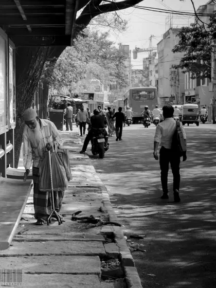 A black and white street scene showing people of different ages walking on the sidewalk. It’s a classic representation of the flow of life in a city.