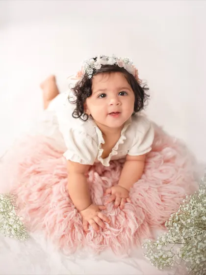 Lying on her tummy on a soft pink rug, this eleven-month-old looks right at the camera. This pose is great for showing off their strength and curiosity.