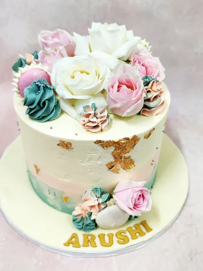 We create a botanical wonderland with this buttercream floral cake. A beautiful bouquet of fresh white and pink roses is artfully arranged with piped succulents in shades of teal and pink, accented with gold leaf for a touch of modern glamour.