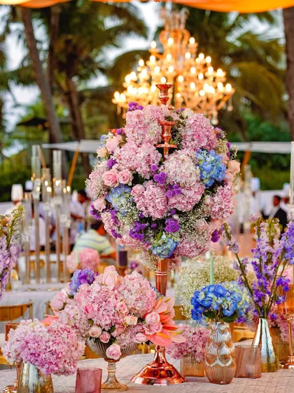 A daytime view of the pastel floral arrangements, showcasing the vibrant pinks and blues against the backdrop of a sunny outdoor setting. The chandelier adds a touch of unexpected glamour to the daytime event.