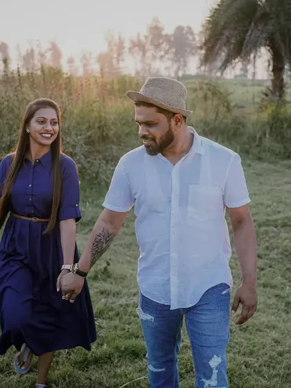 A casual walking shot in a green field, capturing a relaxed and happy pre-wedding moment.