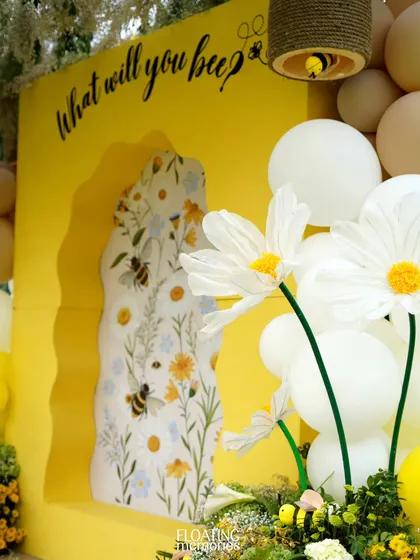A detail of the main photo backdrop, showing the intricate floral-and-bee print insert and the large, handcrafted daisies. This combination of 2D and 3D elements created a rich, textured look.