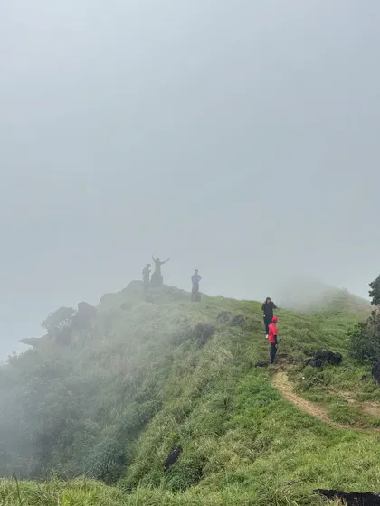 Trekkers making their way up a misty ridge on Kumara Parvatha. The landscape often feels like walking in the clouds.