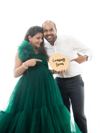A fun "Coming Soon" announcement where both parents-to-be point excitedly at the baby bump and the sign.