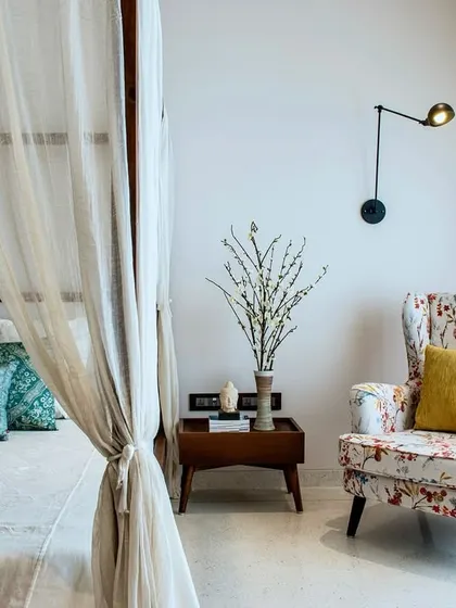 A detail shot from the Terrazzo Residence bedroom, showing a comfortable, floral-patterned armchair that creates a perfect reading corner by the window.