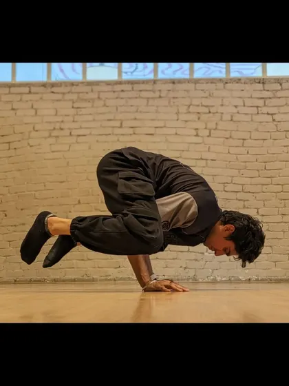 A student holds a challenging crow pose, demonstrating the balance and arm strength we develop through our training.
