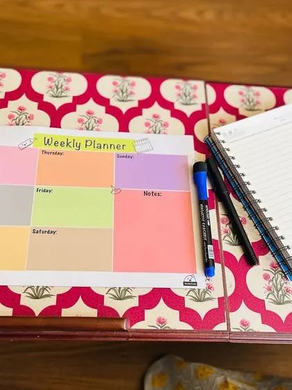 This is my reusable weekly planner, a simple whiteboard-style sheet to organize your week. It comes with a marker that has a duster on the cap.