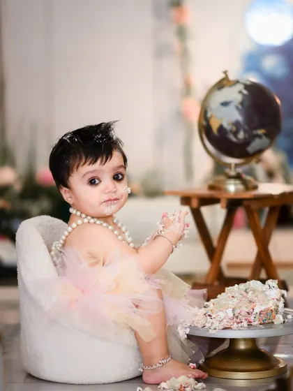 Our cake smash sessions are all about capturing your baby's curiosity and delight. This setup includes a miniature armchair and a globe prop, adding a touch of whimsy to the classic cake smash theme.