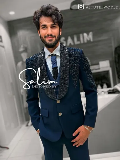 A client wearing a navy blue three-piece suit with heavily embellished lapels. The shawl collar design is a modern take on classic tuxedo styling.