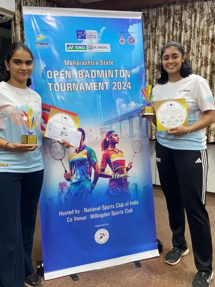 Standing proud in front of the tournament banner, our women's doubles silver medalists showcase their trophies and certificates.