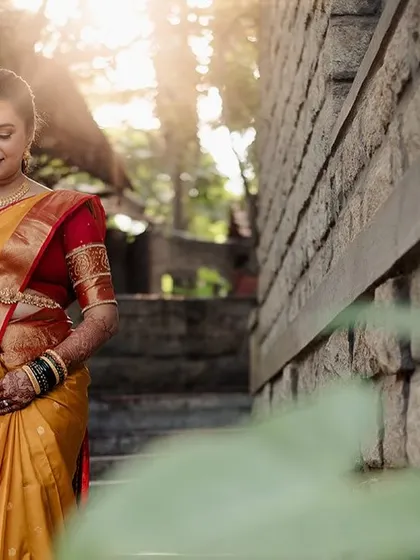 A bride descends a stone staircase, the golden hour light filtering through the leaves, creating a magical and radiant effect.