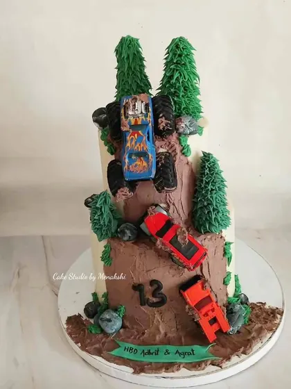 An off-road adventure themed cake for a 13th birthday. This two-tier cake looks like a muddy mountain trail with monster trucks making their way to the top.