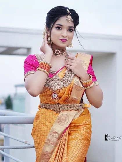 A beautiful outdoor shot from a bridal photoshoot. The makeup is bold and defined, standing out beautifully against the bright sky.