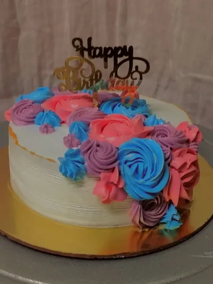 A vibrant and joyful cake featuring a cascade of multi-colored buttercream flowers. The combination of pink, purple, and blue makes this a festive choice for a happy birthday.