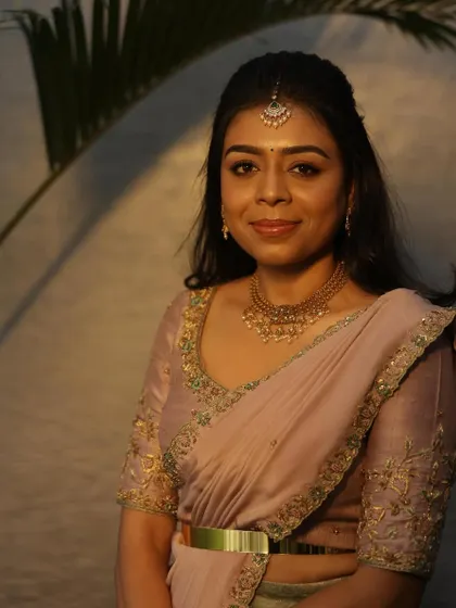 A close-up portrait of Dr. Tushara, her subtle makeup and elegant jewelry perfectly complementing the pastel outfit.