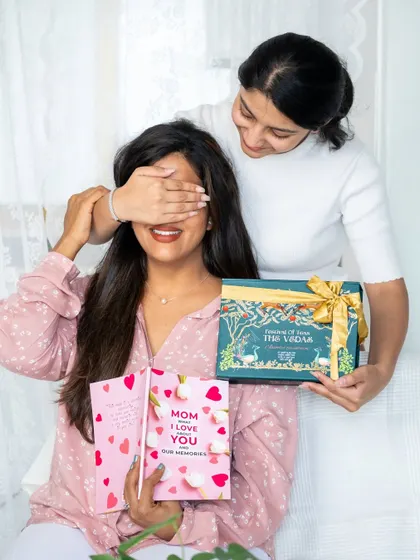 A playful surprise for Mother's Day, with a daughter covering her mom's eyes before presenting a gift.