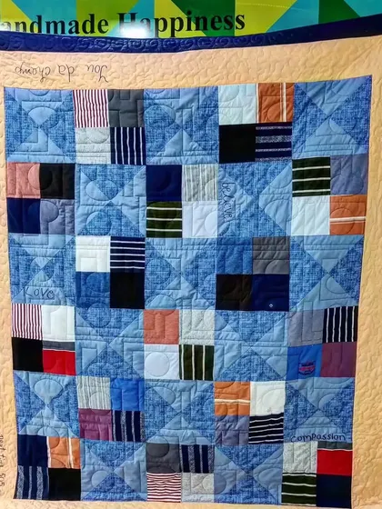 A full view of a T-shirt memory quilt with a warm peach border and personalized quilted messages.