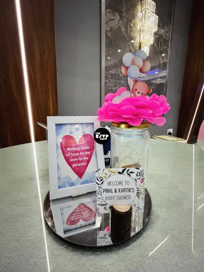 A personalized welcome display for the parents-to-be. We combined a custom welcome sign with a framed message and a decorative jar topped with a teddy bear, creating a warm and inviting first impression for guests.