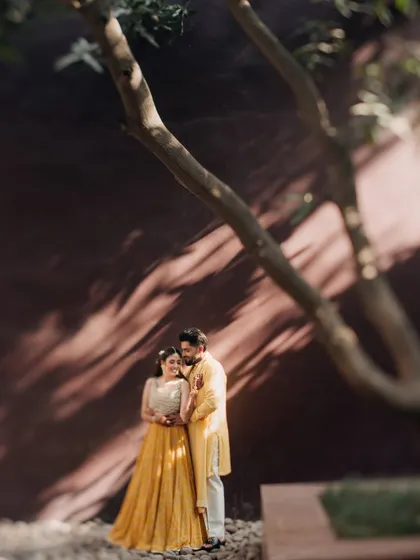 A romantic embrace under the dappled light of a tree. This photo from a Haldi celebration has a soft, dreamy quality.