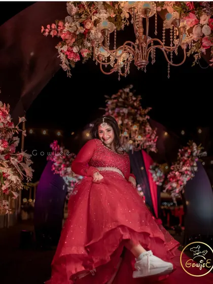 The bride having a fun, candid moment, showing off her sneakers under her beautiful red gown.