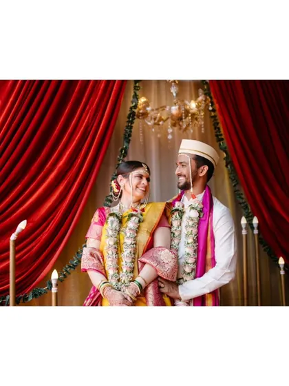 A beautifully framed portrait of the couple against a rich red curtain, symbolizing the love and passion of their union.