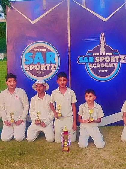 A winning cricket team poses with their trophies.