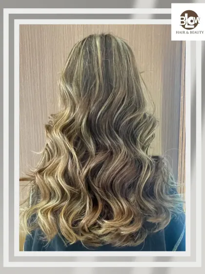 Beautifully styled blonde balayage with soft, flowing waves. This look is all about creating a glamorous yet effortless vibe.