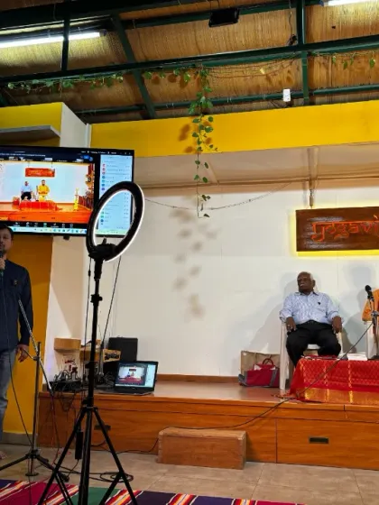 A speaker interacting with the online audience during a hybrid Yoga Vichara session.