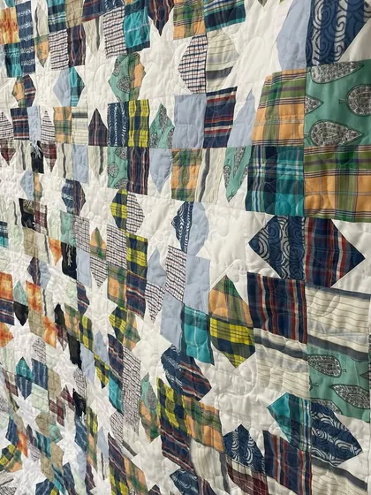 A detailed shot of the Sawtooth Star shirt quilt, showing the variety of plaid, striped, and printed fabrics used.